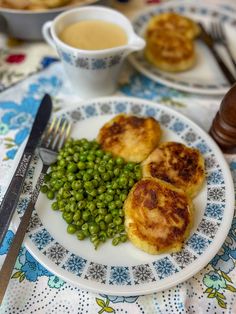 a plate with peas and biscuits on it next to a fork, knife and spoon