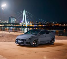 a grey car parked in front of a bridge at night