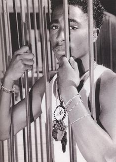 a man is standing behind bars in a jail cell with his hands on the bars