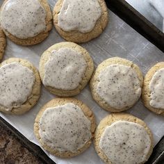 twelve cookies with white icing on a baking sheet