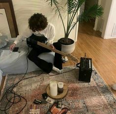 a person sitting on the floor playing an electric guitar