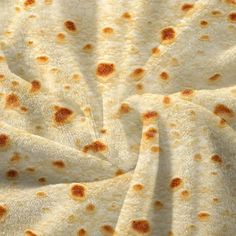 a close up view of some food on a tablecloth that is white with brown spots