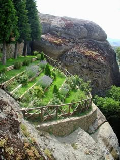 an outdoor garden on the side of a large rock with stairs leading up to it