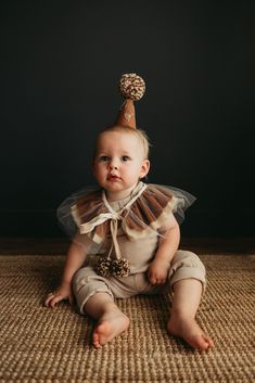 a baby sitting on the floor wearing a party hat