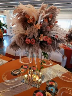 there is a tall vase with feathers and flowers in it on top of the table