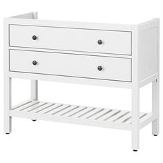 a white baby crib with two drawers and a shelf on the bottom that is holding an infant's diaper