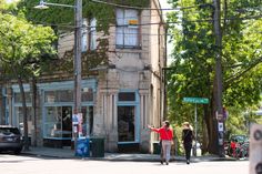 two people crossing the street in front of an old building with ivy growing on it