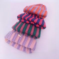 four knitted hats stacked on top of each other in different colors and sizes,