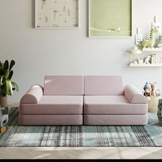 a living room with two pink couches in front of pictures on the wall and rug