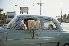 an old blue car with ice cream in the back window and people sitting inside it