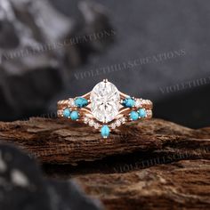 an engagement ring with turquoise stones and diamonds on top of a piece of driftwood