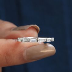 a woman's hand holding an engagement ring with three baguettes