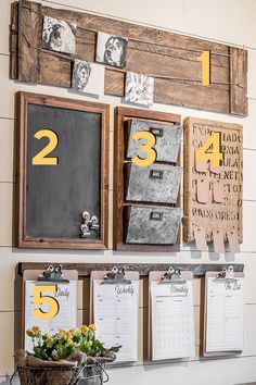 calendars are hung on the wall with wooden frames and flowers in a bucket next to them