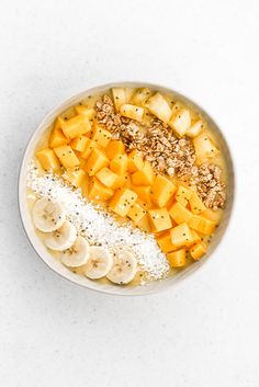 a white bowl filled with bananas, granola and other toppings on top of it