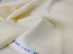 a white cloth with blue stitching on the edge and an embroidered line down the middle