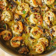 a pan filled with shrimp and mushrooms on top of a wooden table