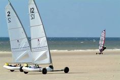 two small sailboats on the beach near the ocean