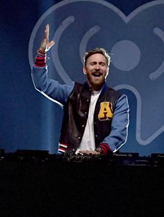 a man with his hand up in the air while standing at a keyboard on stage