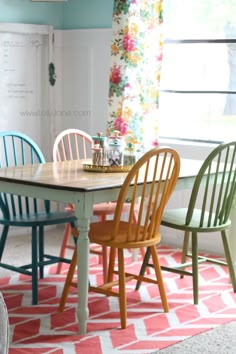 a dining room table with four chairs and a rug on the floor in front of it