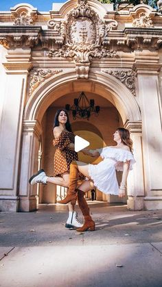 two women are dancing in front of an archway