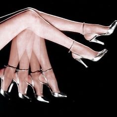 two women's legs in high heeled shoes with their hands on each other