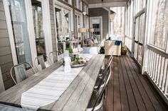 an outdoor dining area with wooden floors and white table cloths on the long table