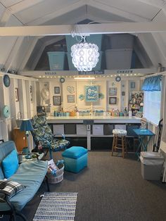 a living room filled with furniture and a chandelier hanging from the ceiling in front of a kitchen