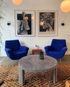 a living room with two blue chairs and a coffee table in front of them on top of a rug