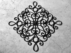 a black metal wall decoration on a white marble floor with an intricate design in the center