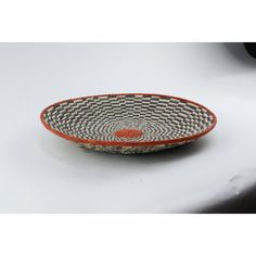 an orange and black bowl sitting on top of a white table next to a car