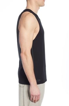 a man wearing a black tank top and grey sweatpants standing in front of a white background