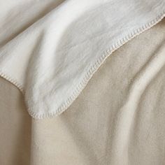 an unmade bed with white sheets and pillows