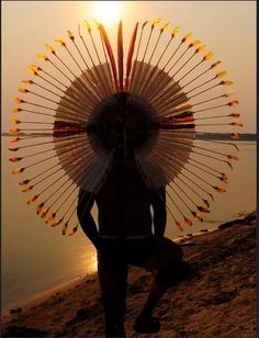 a person with an umbrella on their head standing by the water at sunset or sunrise