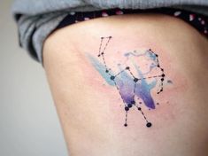 a watercolor tattoo on the side of a woman's thigh, showing her zodiac sign