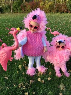 two pink flamingos are standing next to each other in the grass with sunglasses on