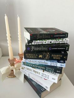 a stack of books sitting on top of a white table next to a lit candle