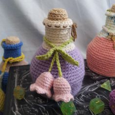 three crocheted bottles sitting next to each other on top of a black table