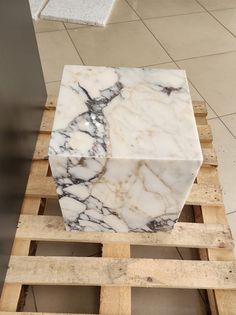 a marble block sitting on top of wooden pallets in a room with tile flooring