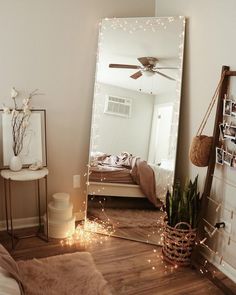 a large mirror sitting on top of a wooden floor next to a wall mounted fan