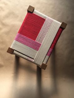 a red and white striped book sitting on top of a wooden stand next to a wall