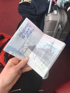 someone is holding up a passport in front of their suitcases at an airport or train station