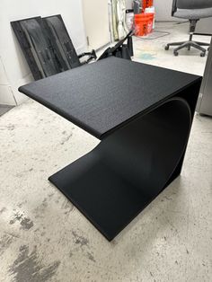 a black table sitting on top of a white floor next to a chair and desk