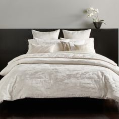 the bed is made with white linens and pillows