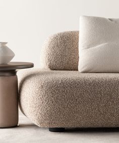 a beige couch sitting next to a table on top of a white carpeted floor