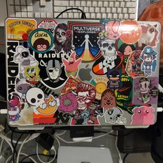 a laptop covered in lots of stickers sitting on top of a desk