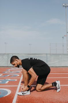 a man kneeling down on top of a red running track