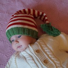 a baby is wearing a striped hat and sweater