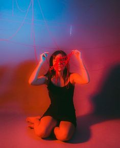 a woman sitting on the floor with her hands in front of her face and wires above her head