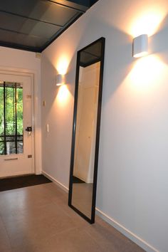 an empty room with a large mirror on the wall and two lights on the door