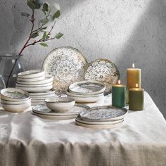 a table topped with plates and candles next to a vase